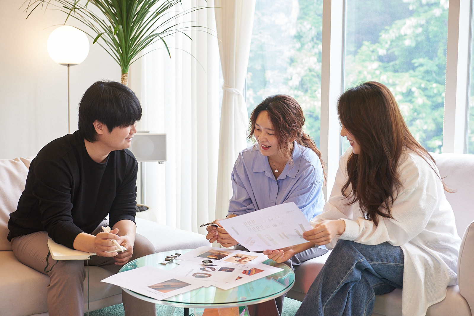 브랜드 회의에서 자료를 함께 검토하며 대화하는 박시하와 팀원들